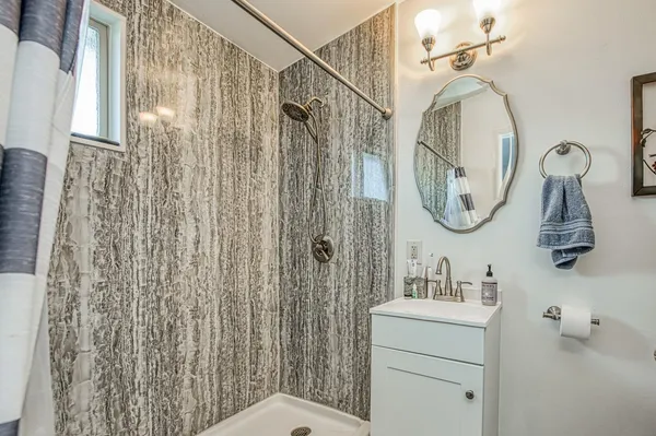 a bathroom with a sink a mirror a vanity and a shower