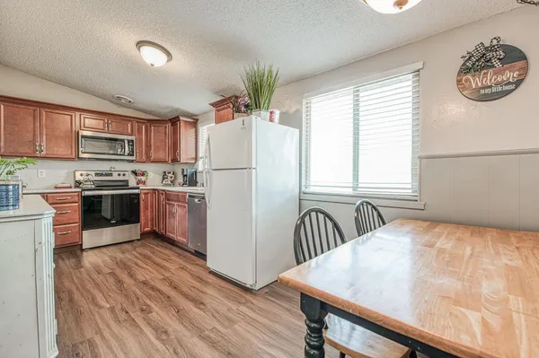 a kitchen with stainless steel appliances granite countertop a refrigerator a stove and a wooden floors