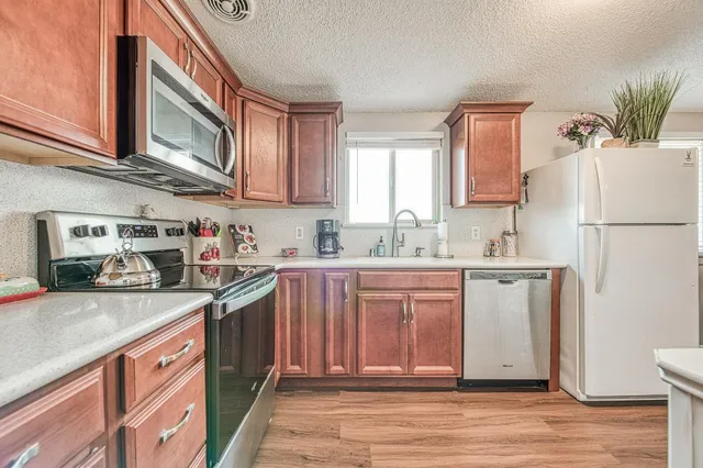a kitchen with stainless steel appliances granite countertop a stove a sink dishwasher and a refrigerator with white cabinets