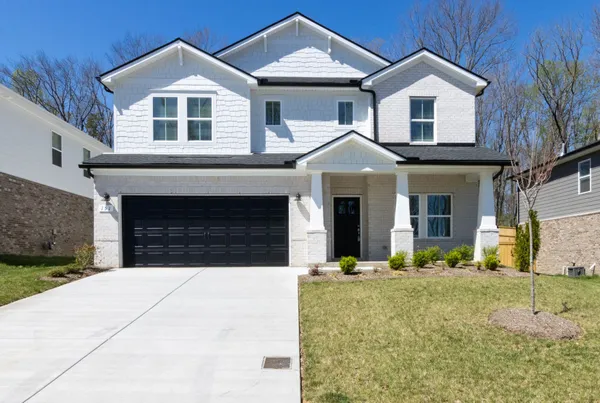 a front view of a house with yard and parking