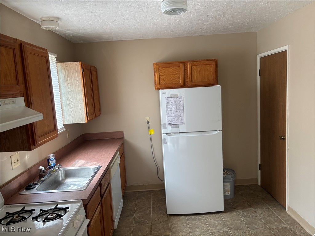 4181 New Road Youngstown, OH 44515 - Photo 5 of 11 Kitchen featuring white appliances, brown cabinets, extractor fan, a textured ceiling, and light countertops