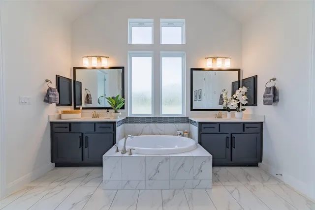 a spacious bathroom with a tub sink and mirror
