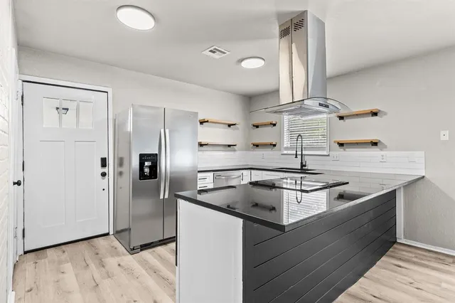a kitchen with stainless steel appliances granite countertop a sink and a refrigerator