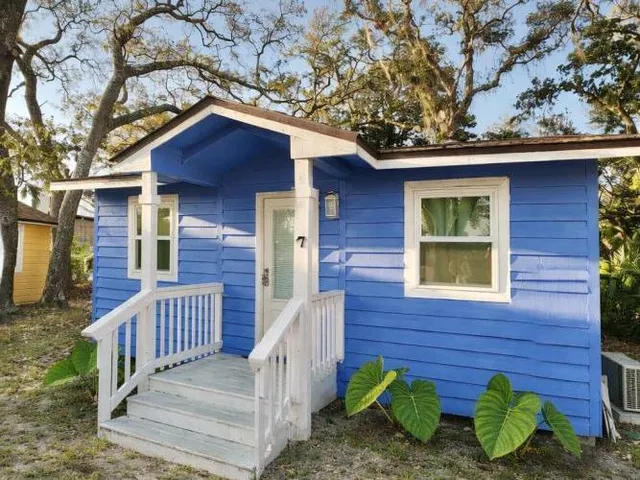 a view of a wooden house with a small yard and wooden fence