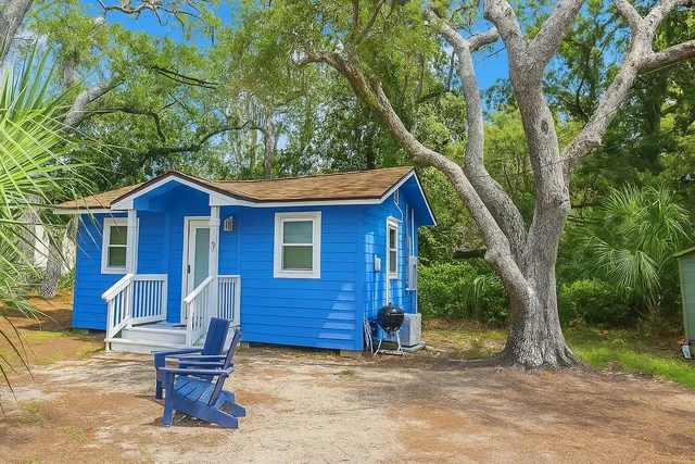 a view of a house with wooden fence and large trees