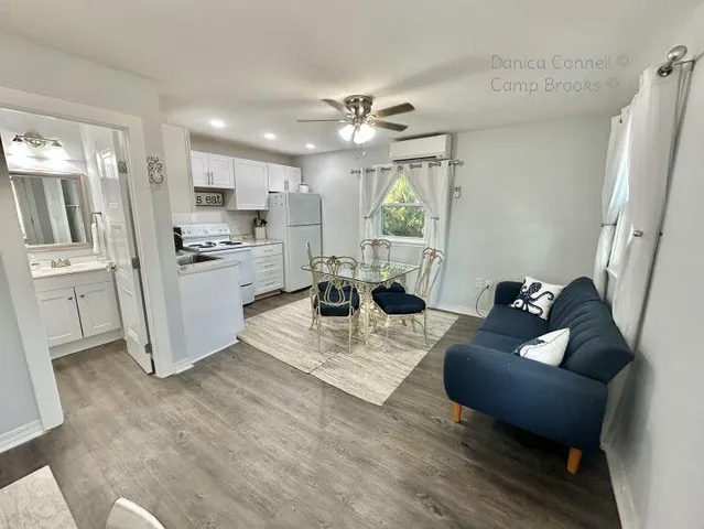 a living room with stainless steel appliances furniture a rug and a view of kitchen