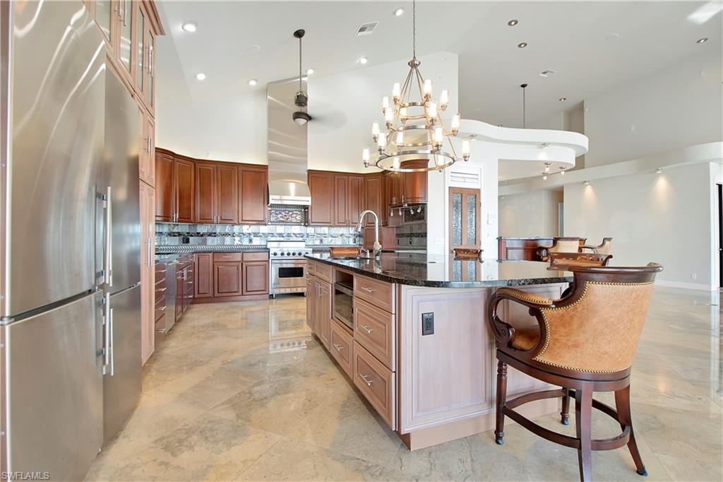 28 West Pelican Street Naples, FL 34113 - Photo 11 of 50 a kitchen with kitchen island granite countertop wooden cabinets and refrigerator