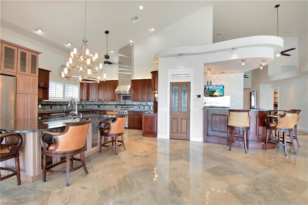 28 West Pelican Street Naples, FL 34113 - Photo 12 of 50 a kitchen with kitchen island a dining table and chairs
