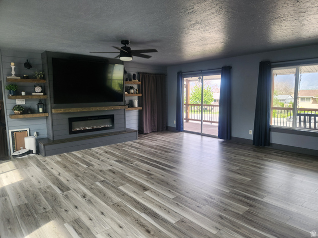 705 North 700 East Payson, UT 84651 - Photo 8 of 30 Unfurnished living room featuring a ceiling fan, a textured ceiling, a glass covered fireplace, and dark wood finished floors