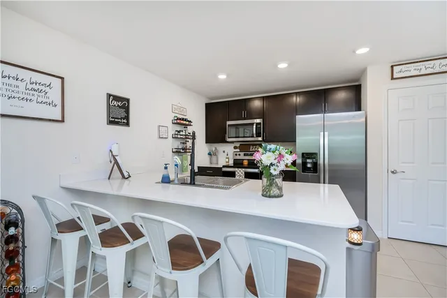 a kitchen with stainless steel appliances a dining table chairs refrigerator and microwave