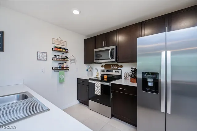 a kitchen with stainless steel appliances granite countertop a refrigerator a stove and a sink with wooden floor