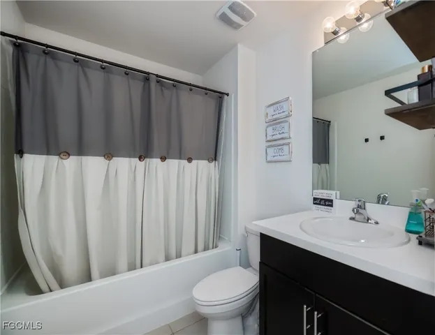 a bathroom with a sink a toilet a mirror and shower curtain