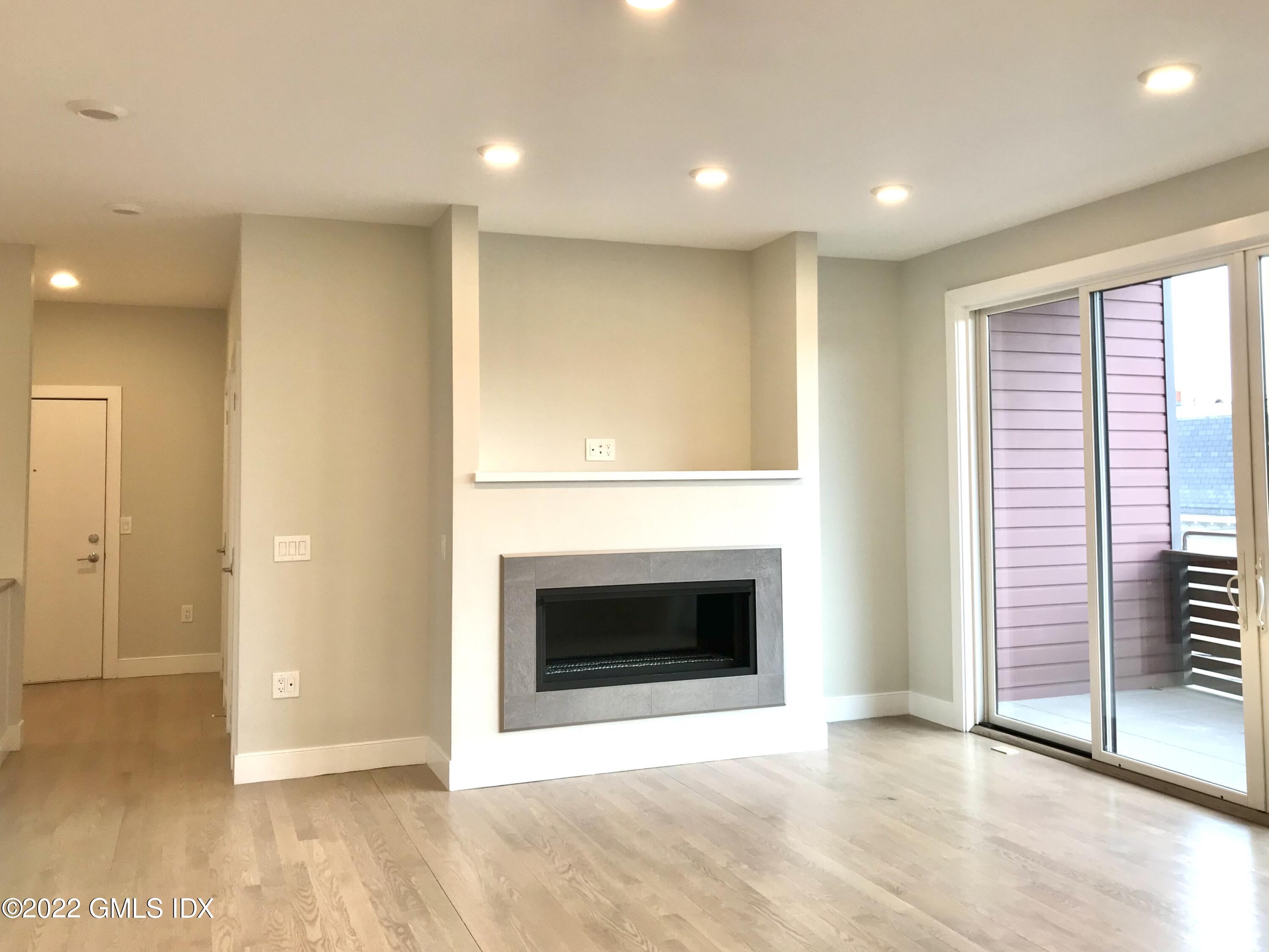 56 Old Field Point Road, Unit 1 Greenwich, CT 06830 - Photo 16 of 30 an empty room with wooden floor fireplace and windows