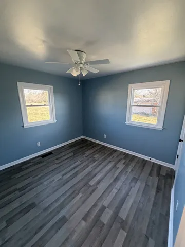 a view of an empty room with a window and wooden floor