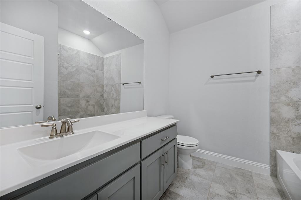 15862 Shasta Daisy Road Frisco, TX 75035 - Photo 14 of 15 Upstairs bathroom has vanity with an integrated sink, brushed nickel fixtures, a large mirror, tiled flooring, full size bathtub.