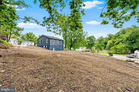 a view of house with a yard and tree in the background