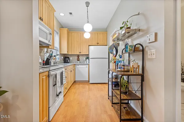 a kitchen with kitchen island granite countertop wooden cabinets and refrigerator