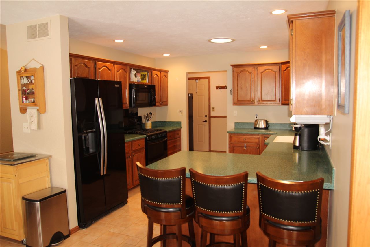7206 Rye Ridge Trail Cherry Valley, IL 61016 - Photo 6 of 25 a kitchen with stainless steel appliances granite countertop a refrigerator a stove a sink a dining table and chairs with wooden floor