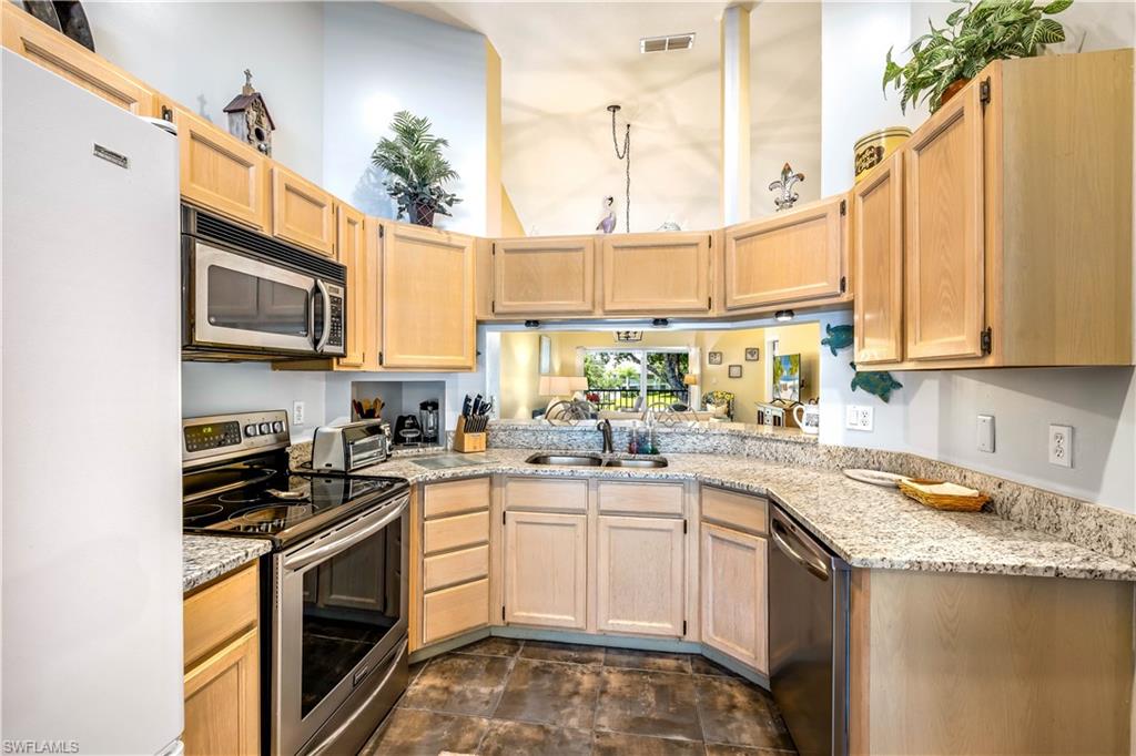 1350 Misty Pines Circle, Unit 204 Naples, FL 34105 - Photo 6 of 19 a kitchen with stainless steel appliances granite countertop a sink a stove and cabinets