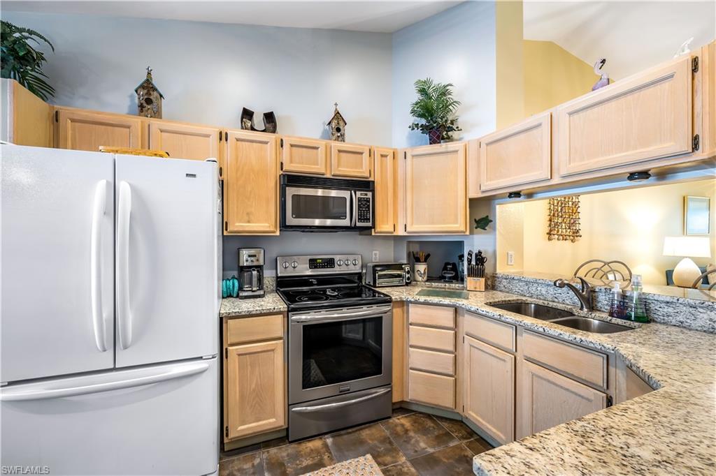 1350 Misty Pines Circle, Unit 204 Naples, FL 34105 - Photo 7 of 19 a kitchen with stainless steel appliances granite countertop a refrigerator sink stove and microwave