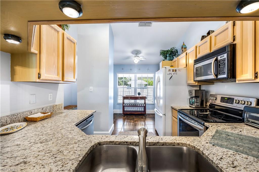 1350 Misty Pines Circle, Unit 204 Naples, FL 34105 - Photo 8 of 19 a kitchen with a stove a sink and a microwave