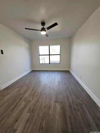 an empty room with wooden floor ceiling fan and windows