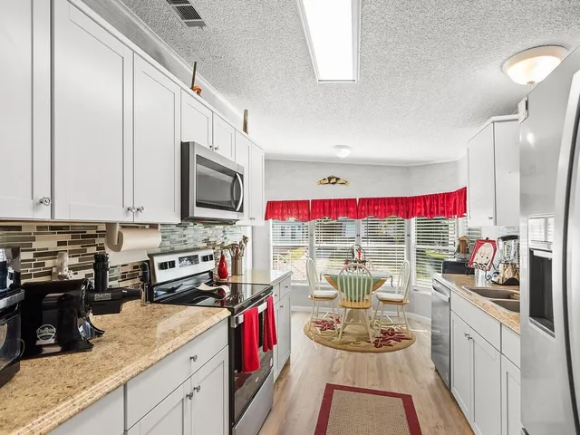 a view of a kitchen with kitchen island granite countertop a sink appliances cabinets and a counter top space