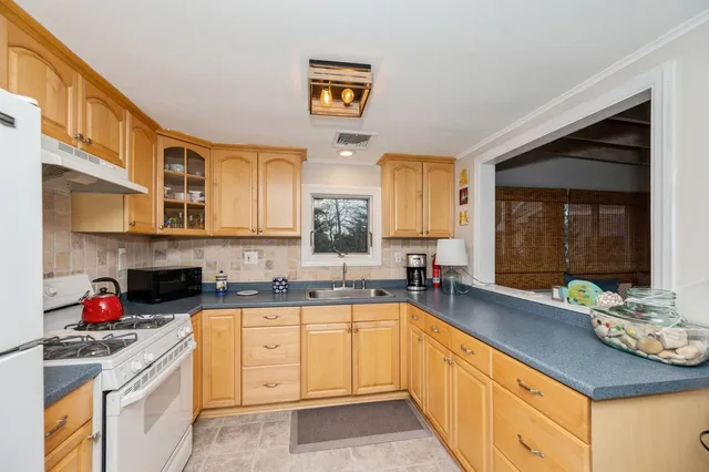 a spacious kitchen with stainless steel appliances granite countertop a sink dishwasher stove and cabinets with wooden floor