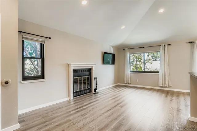an empty room with windows a fireplace and wooden floor