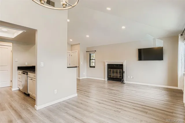 a view of an empty room with wooden floor and a fireplace