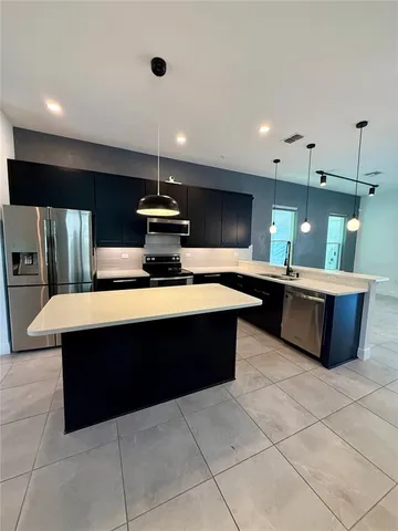 a large kitchen with a counter top space a sink stainless steel appliances and cabinets