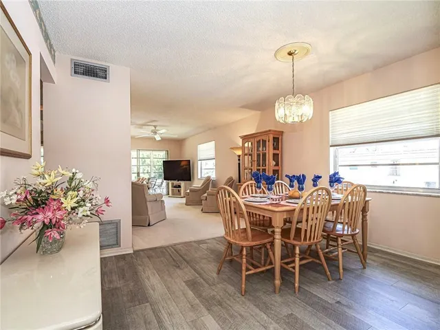 a view of a dining room and livingroom with furniture wooden floor a chandelier