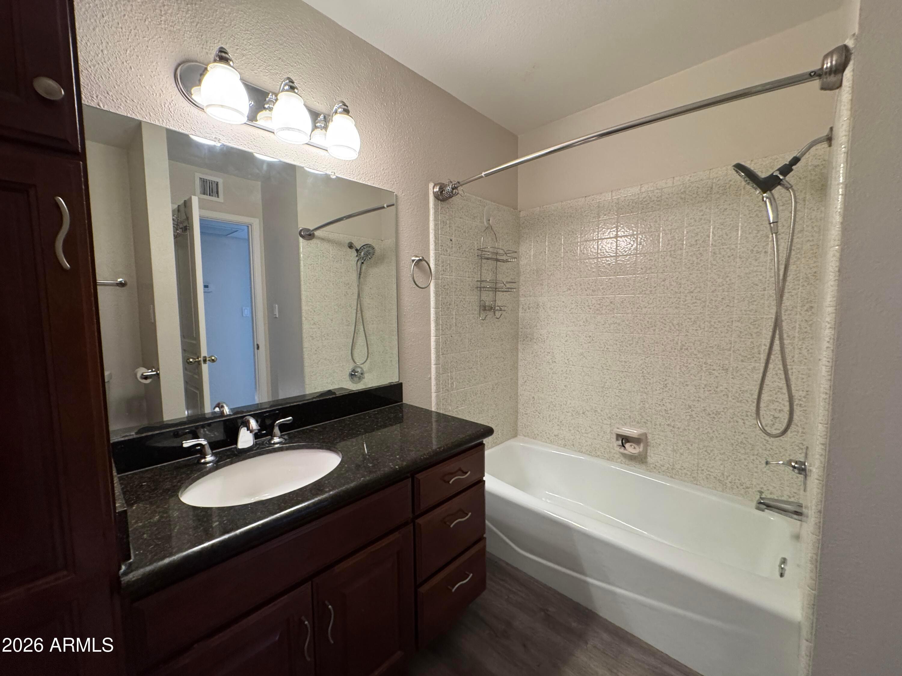 6317 East McLellan Road Mesa, AZ 85205 - Photo 12 of 28 a bathroom with a granite countertop sink a mirror a shower and a bathtub