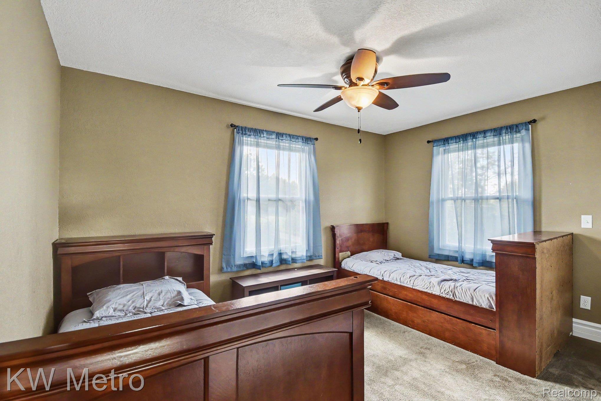 2682 East Haskell Lake Road Harrison, MI 48625 - Photo 29 of 61 Carpeted room featuring a ceiling fan with integrated lighting, textured walls, and two windows with sheer blue curtains