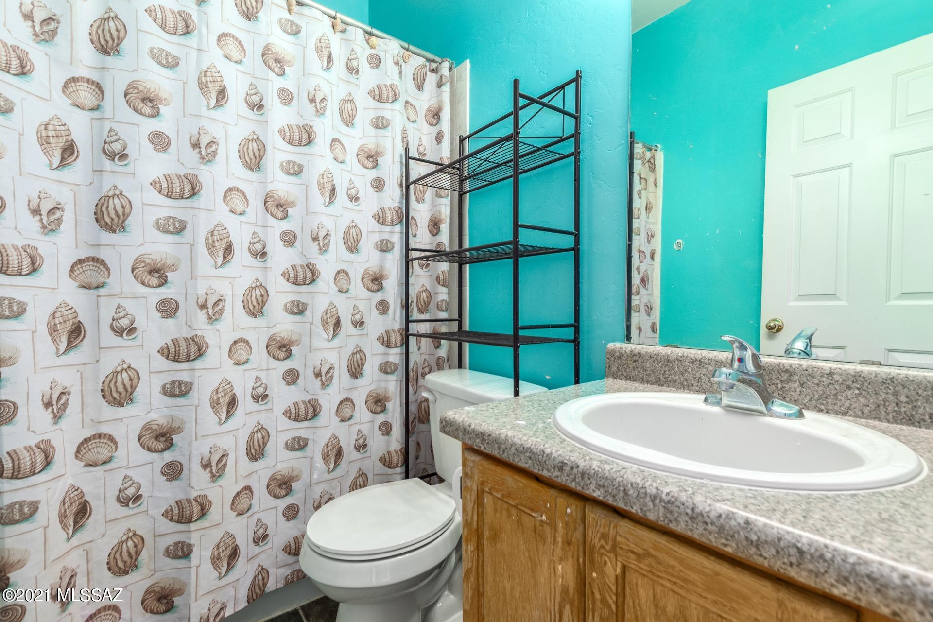 3526 South Mission Road, Unit 3 Tucson, AZ 85713 - Photo 21 of 24 a bathroom with a granite countertop sink a toilet and a mirror