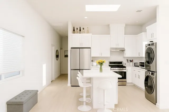 a kitchen with stainless steel appliances a sink a stove a refrigerator cabinets and a dining table