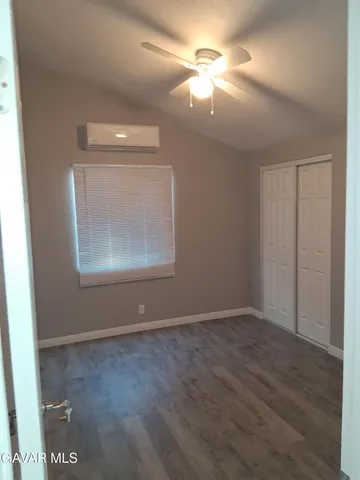 an empty room with wooden floor chandelier fan and windows