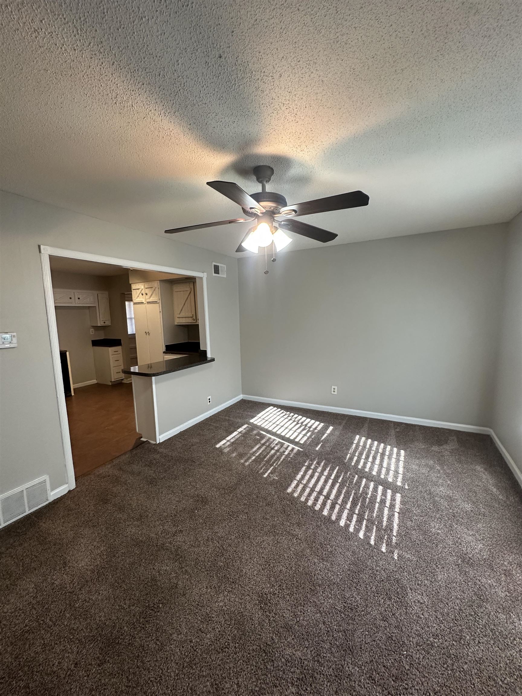 2111 Rock Ridge Road Memphis, TN 38134 - Photo 10 of 20 Unfurnished living room with dark colored carpet, a textured ceiling, and a ceiling fan
