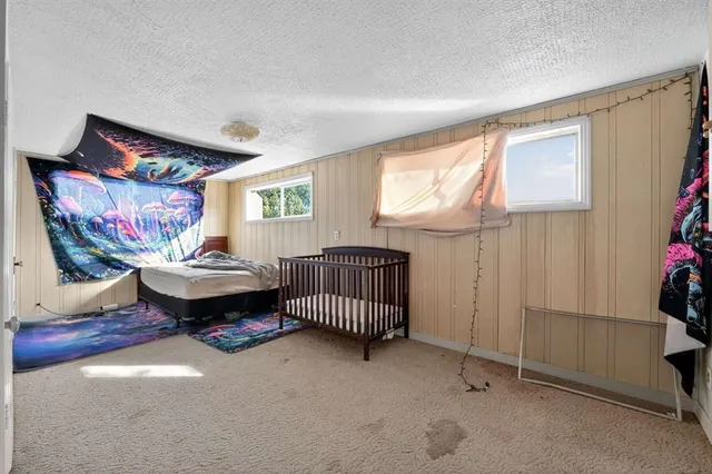 a bedroom with a bed a painting on the wall and a window