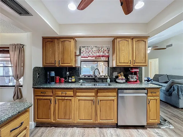 a kitchen with stainless steel appliances granite countertop a sink dishwasher stove refrigerator and cabinets