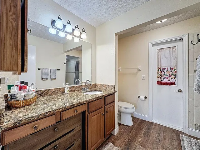 a spacious en suite bathroom with a granite countertop double vanity sink and a mirror