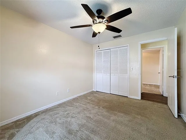 an empty room with windows and fan