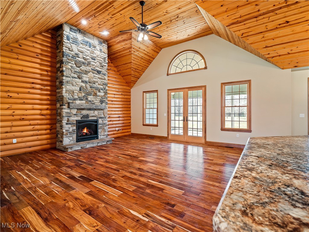 12740 Root Road Columbia Station, OH 44028 - Photo 3 of 47 Unfurnished living room with hardwood / wood-style floors, high vaulted ceiling, ceiling fan, a stone fireplace, and wood ceiling