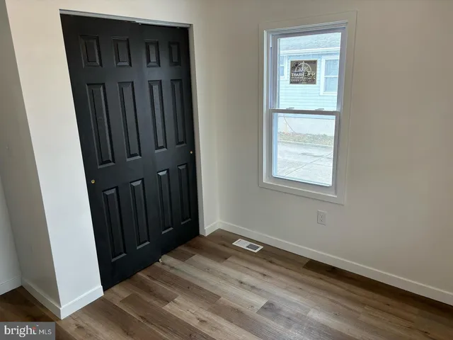 a view of a hallway with wooden floor and closet