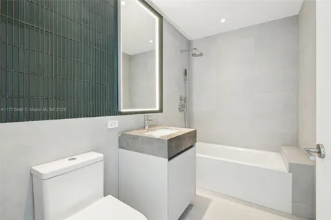 a bathroom with a granite countertop sink a mirror and a bathtub