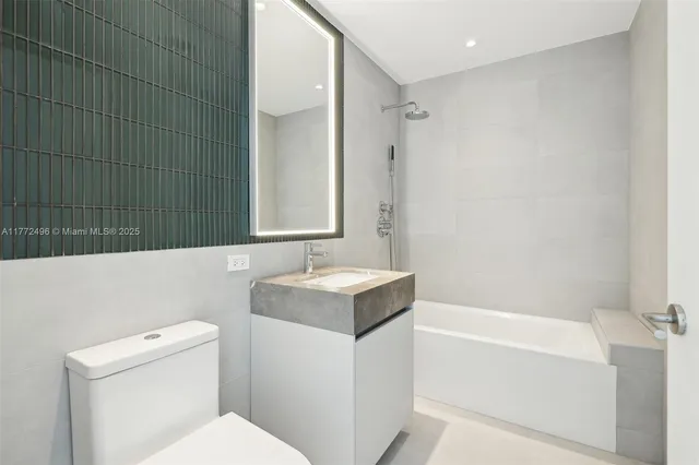 a bathroom with a granite countertop sink a mirror and a bathtub