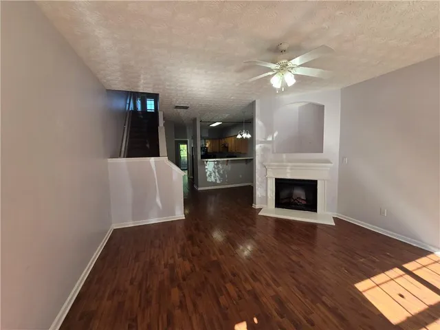 a view of a livingroom with a fireplace a ceiling fan and wooden floor