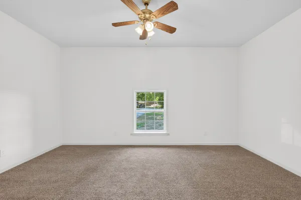 an empty room with a window and a fan