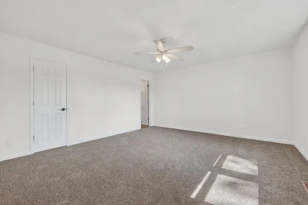 an empty room with a window and a ceiling fan