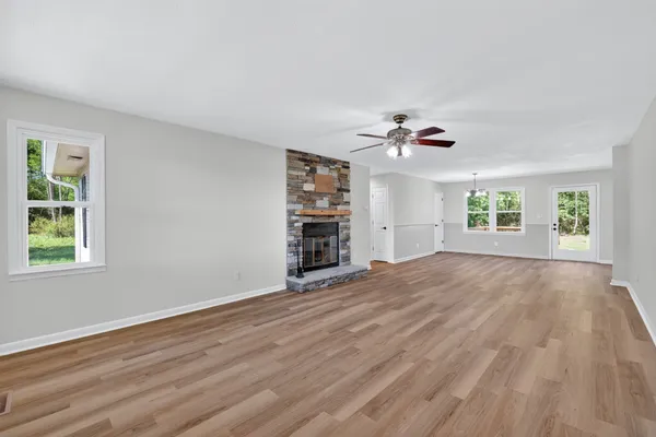 a view of an empty room with a window and wooden floor